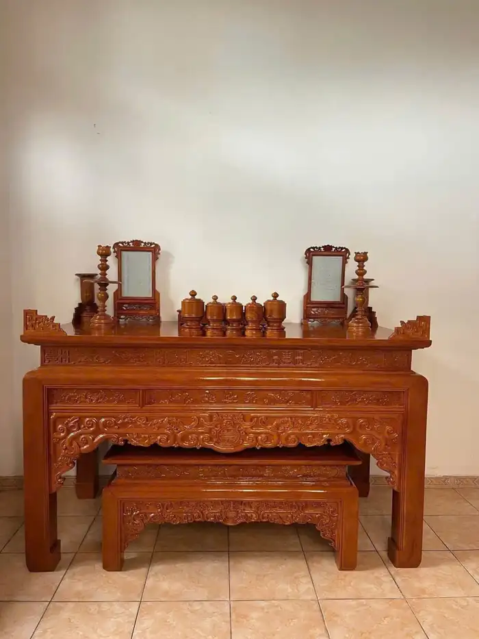 Bàn thờ gỗ với gương thờ chạm khắc và đồ thờ bày hai bên